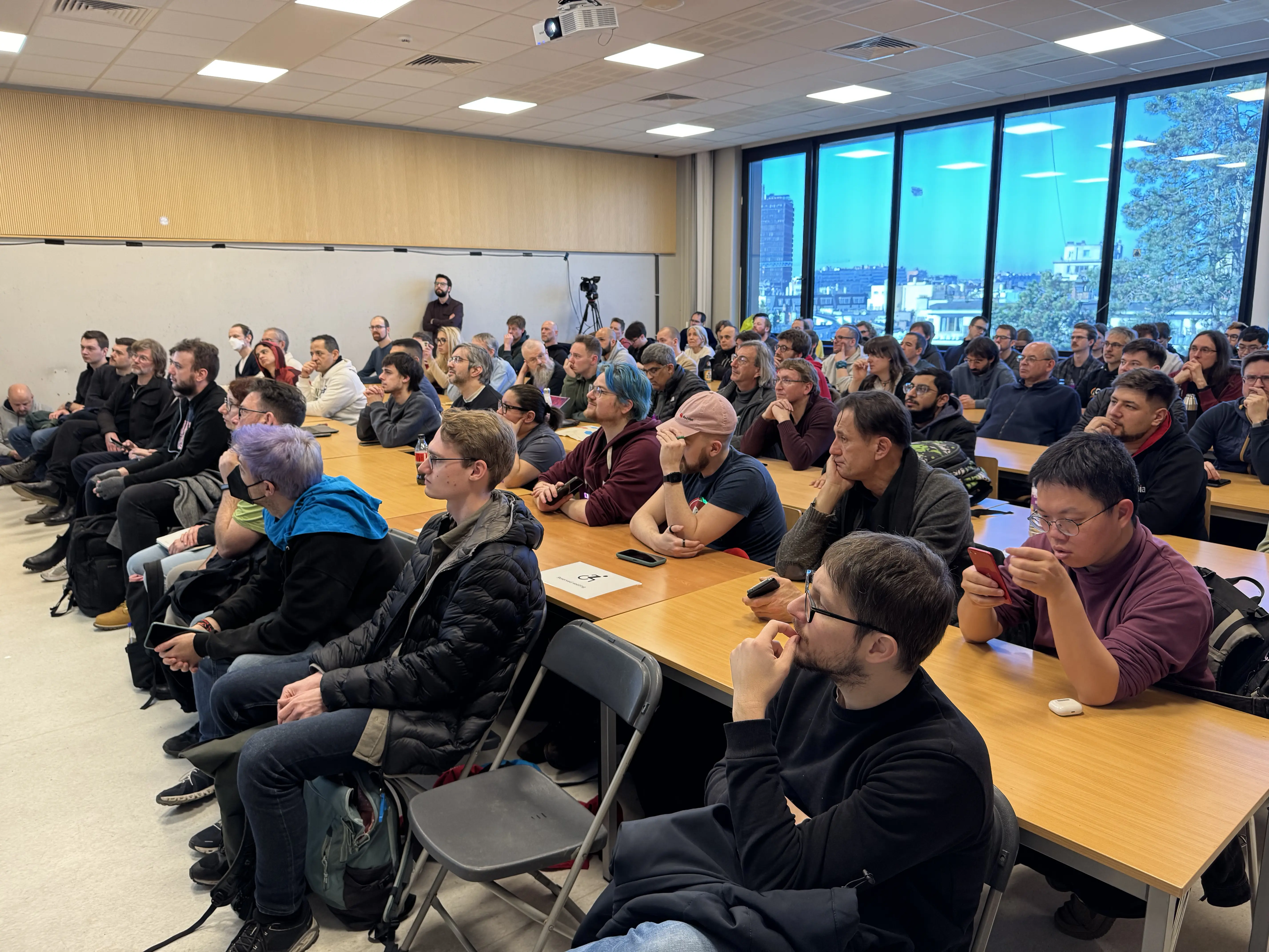 A room full of people are listening to a speaker who is off the frame.